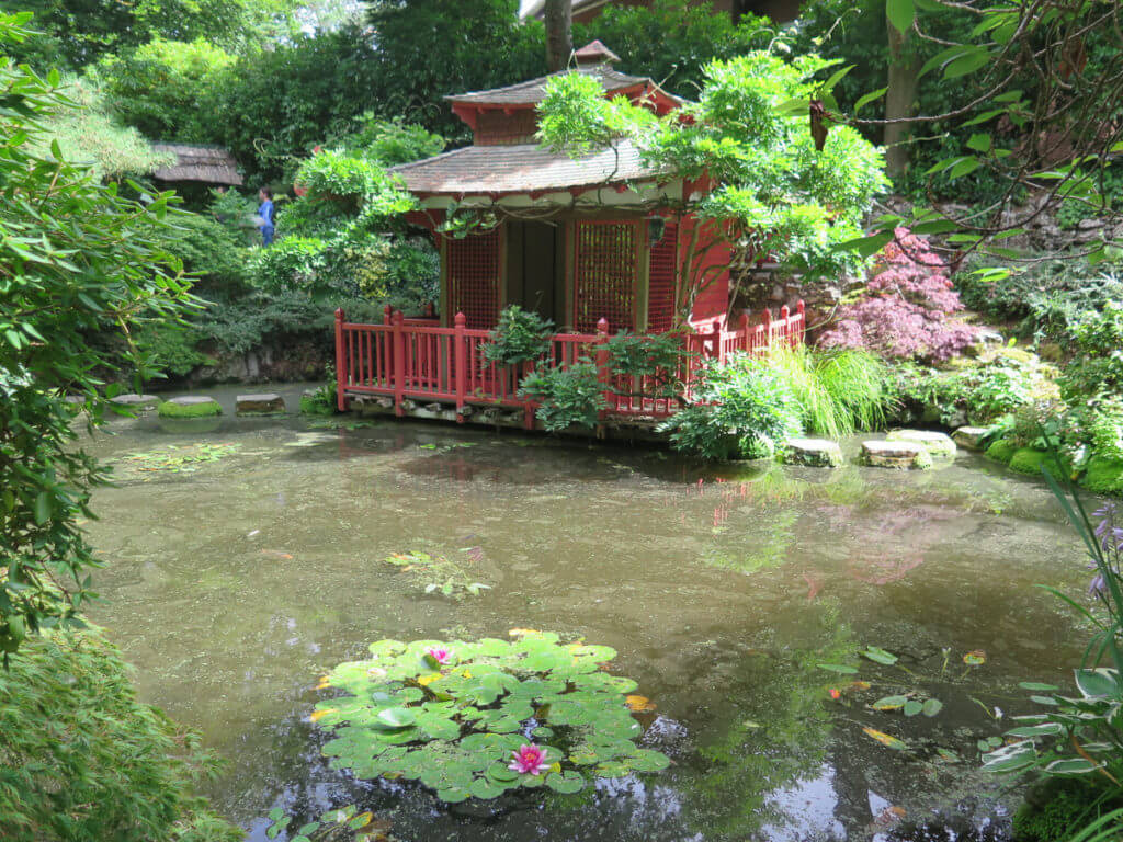 Japanischer Garten mit Häuschen und Seerosen im Vordergrund