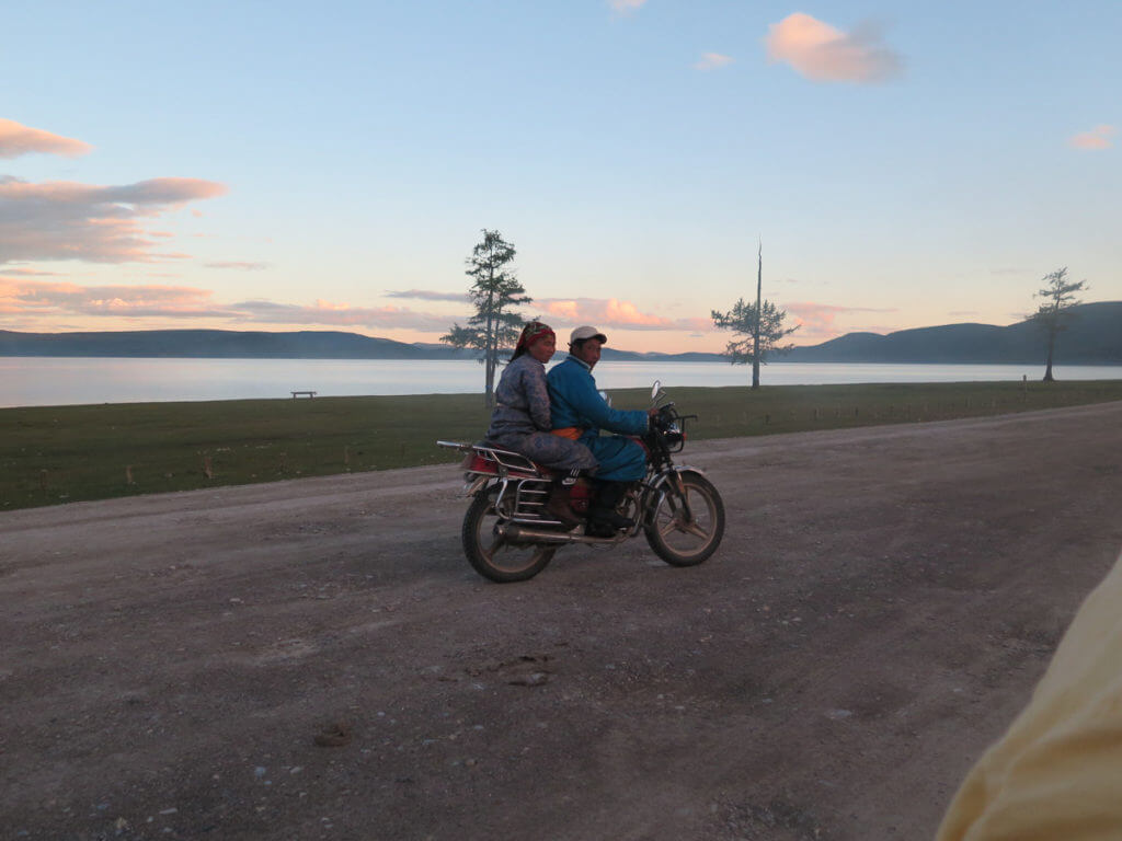 Chuwsgulsee mit mongolisches Paar auf einem Motorrad im Vordergrund