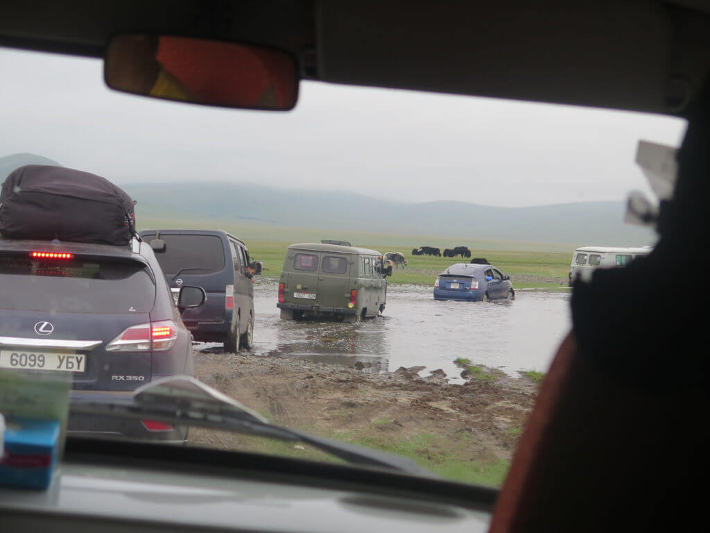 Flussüberquerung, Autos die in Kolonne fahren, im Hintergrund Yaks
