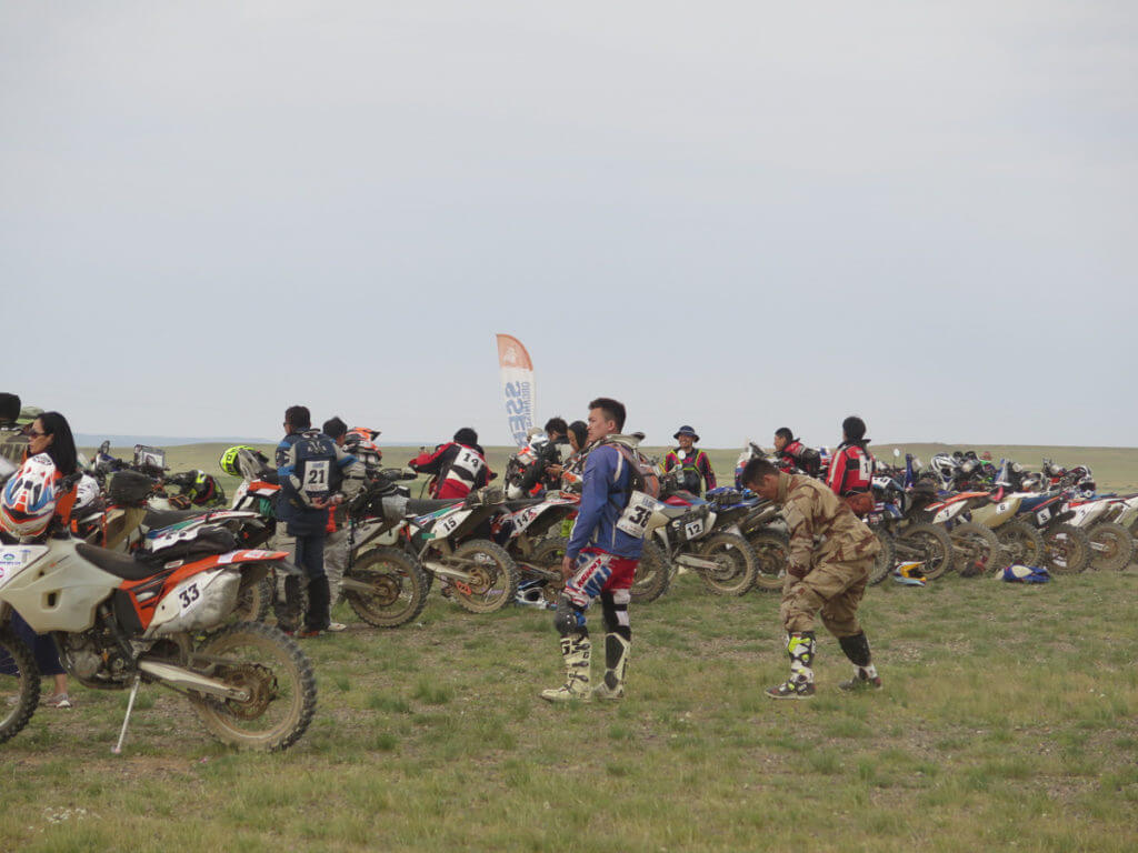 Ralley in der Mongolei, Motorräder aufgereiht für den Start, Fahrer stehen noch daneben