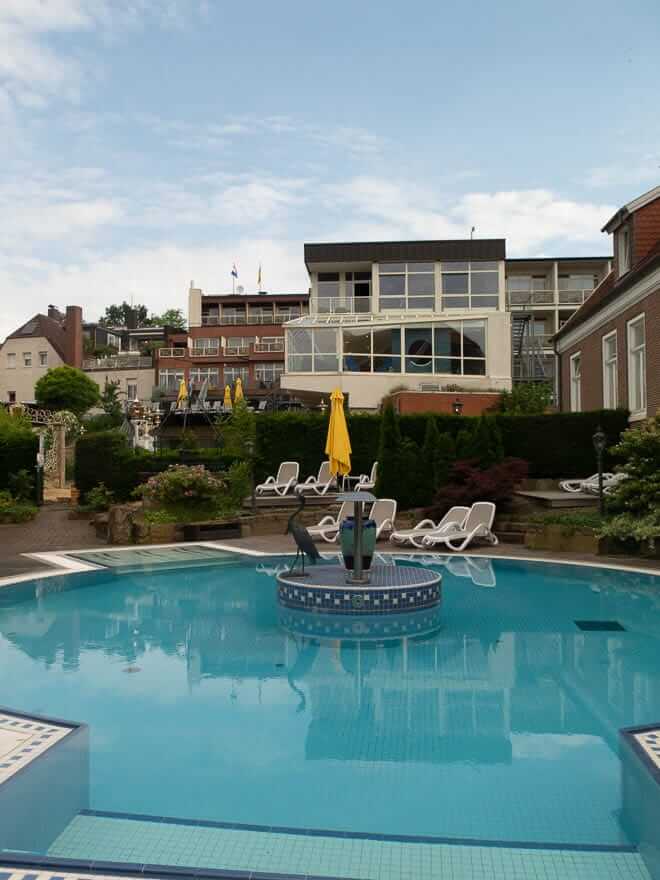 Blick auf Pool und Hinterseite Hotel Grossfeld mit Sonnenliegen und Terrasse