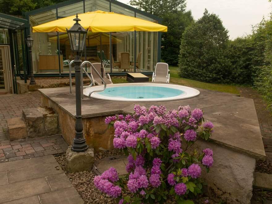 Whirlpool in Hotel Grossfeld mit Rhodondendron vorne und hinten gelber Sonnenschirm