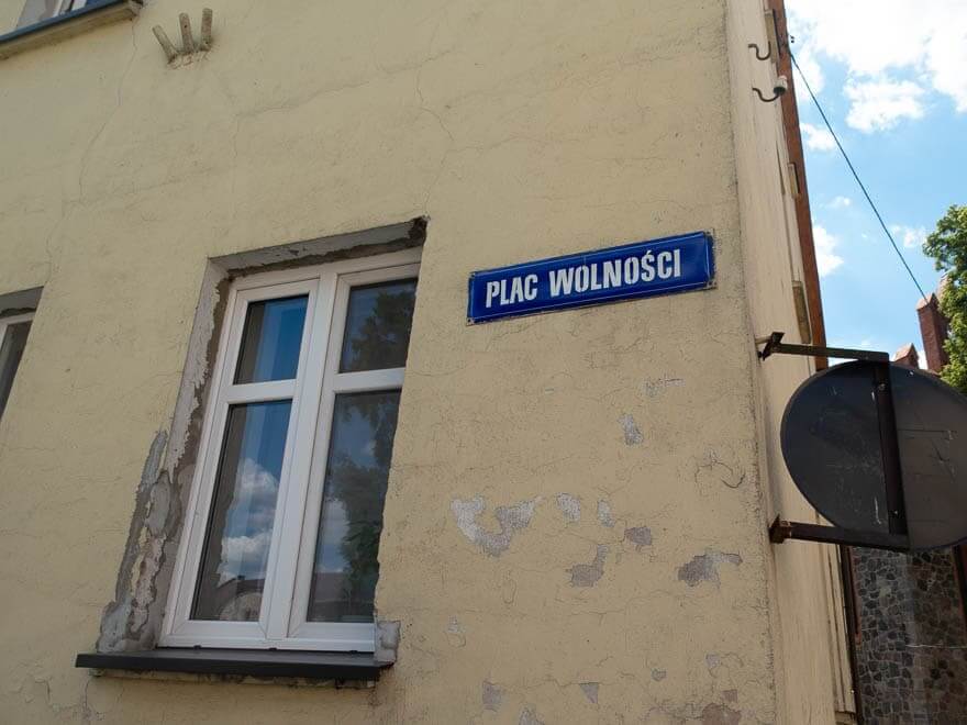 Gelbes Haus mit Schild 'Plac Wolnosci', Fenster