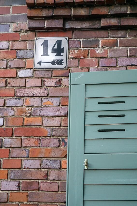 Backsteinwand mit Hausnummer 14 und grüne Fensterladen